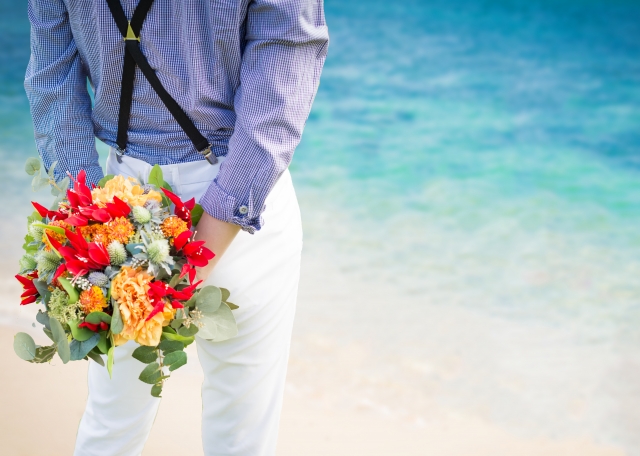 海岸でプロポーズの花束を持つ男性