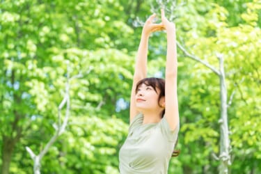 森林で背伸びをする女性